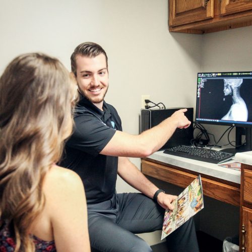 Advantage Family Chiropractic Chiropractor infront of a desktop with a patient